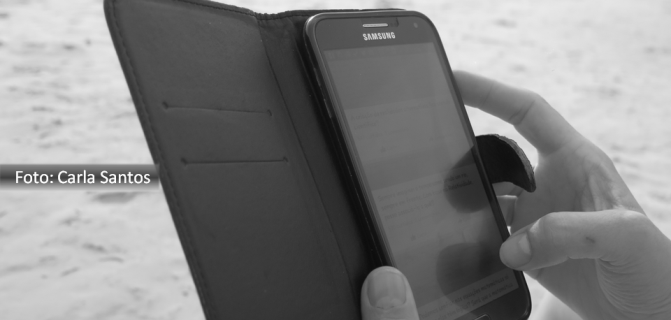 Imagem de alguém usando celular para acessar os e-mails na beira da praia