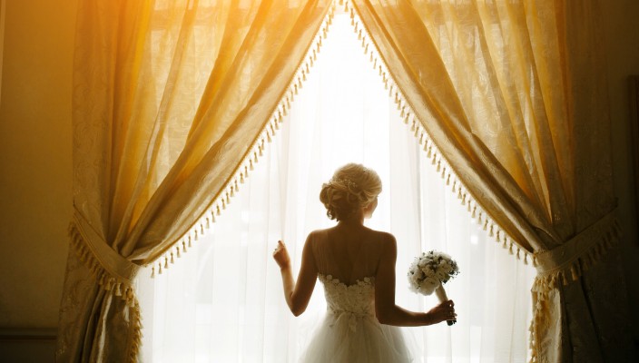 Noiva segurando um ramalhete em frente à janela
